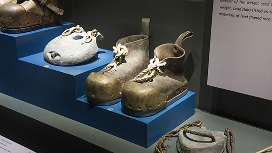 Diving shoes; made in Denmark, brass, lead, wood and stout leather;  Diving weight; made in England (SIEBE GORMAN); lead and brass